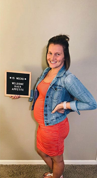 15 weeks pregnant woman showing off baby bump
