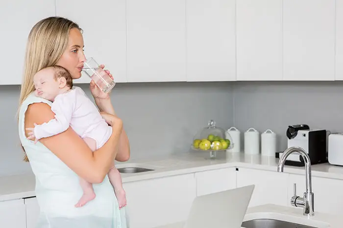 mom drinking placenta tincture while holding her baby