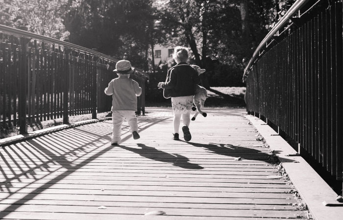 preschoolers playing shadow tag on a bridge