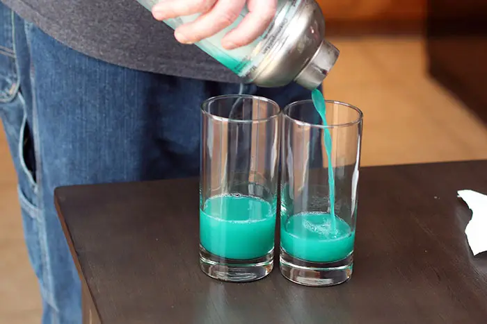 straining liquid from cocktail shaker into two glasses