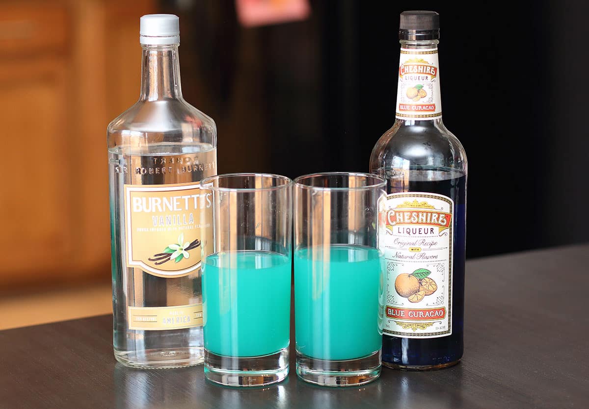 two sonic screwdriver cocktails next to burnett's vanilla vodka and cheshire liqueur blue curacao