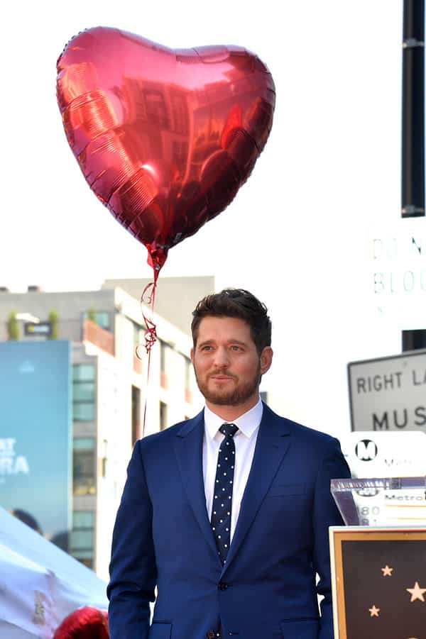 michael buble standing next to red heart mylar balloon