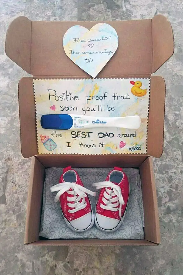 pregnancy test and baby shoes in a box announcement