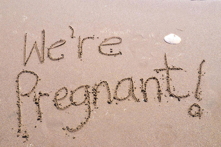 we're pregnant written in the sand on the beach