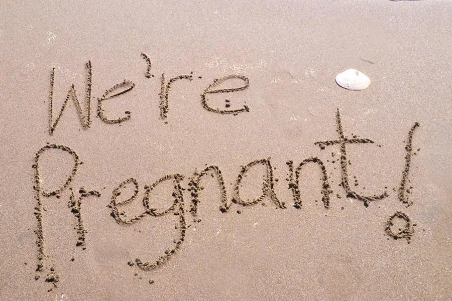 we're pregnant written in the sand on the beach