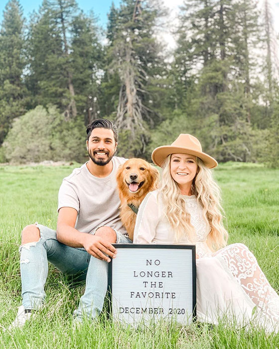 couple with dog announcing their pregnancy with sign that says "no longer the favorite"