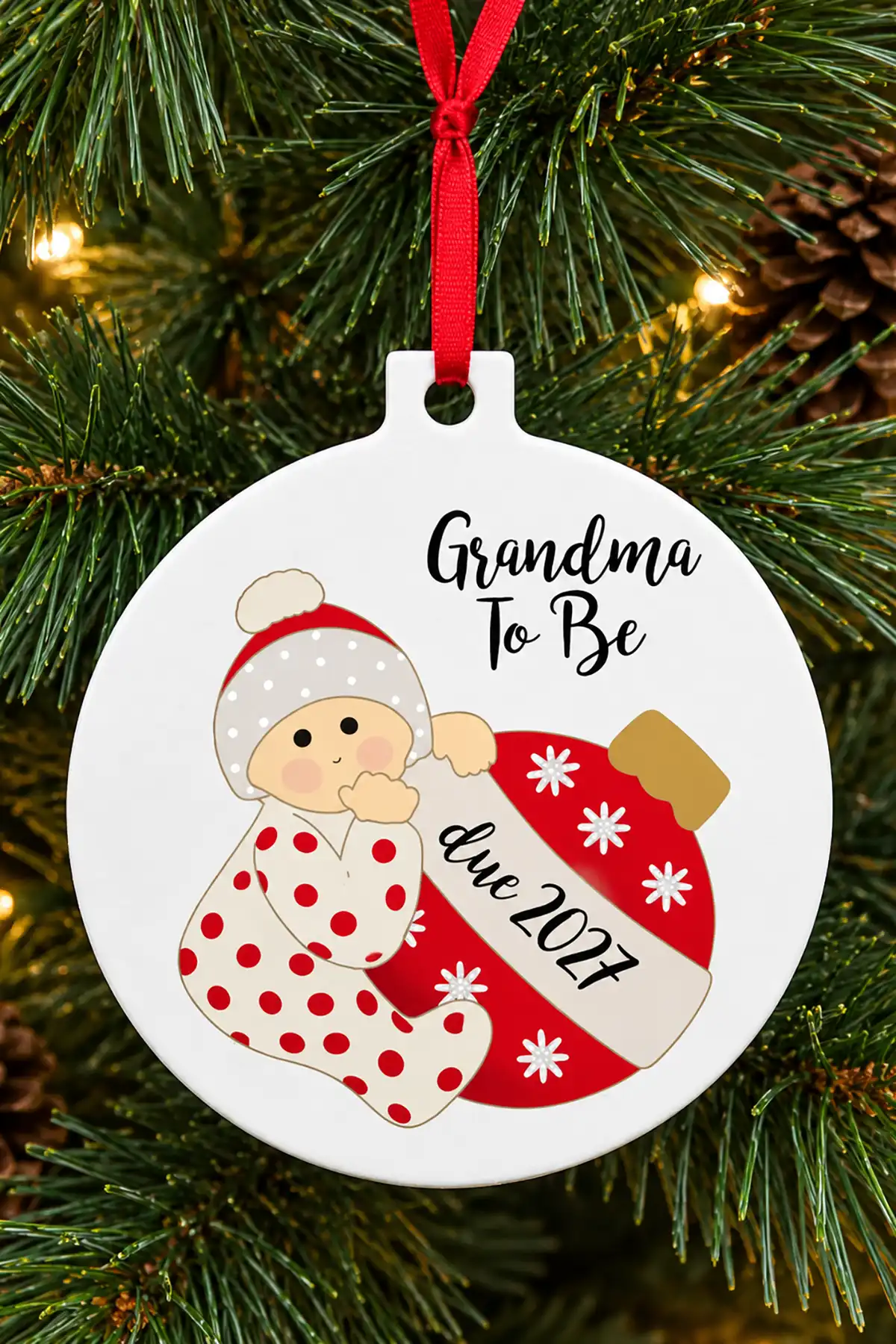 Grandma-to-be pregnancy announcement Christmas ornament with an illustrated baby, red ribbon, and due 2027 message.