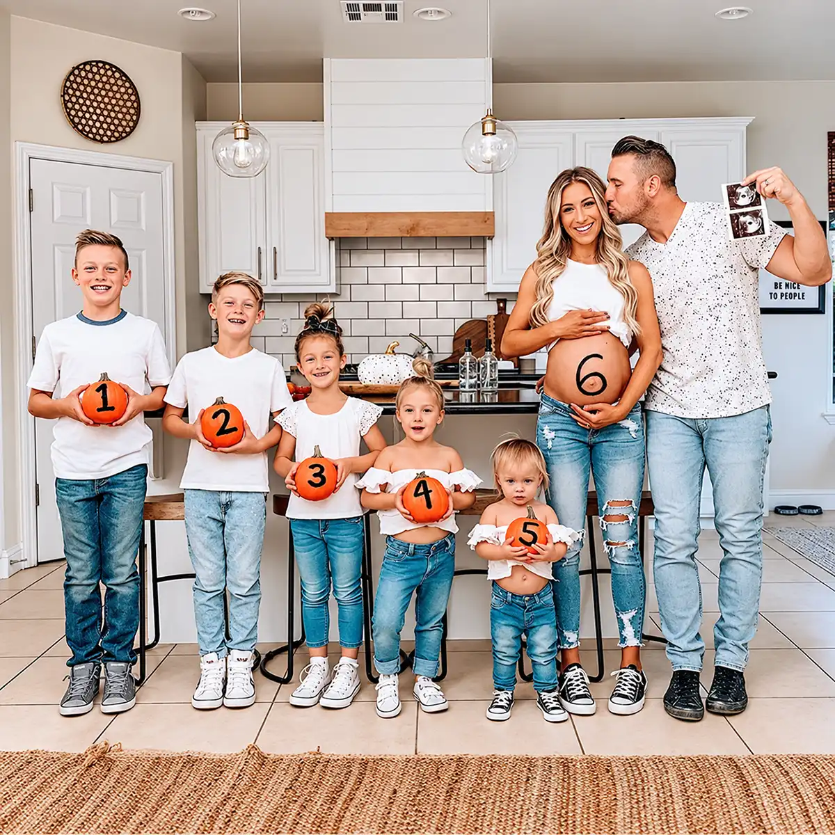Family pregnancy announcement with five children holding numbered pumpkins and pregnant mom showing baby number six on her belly.