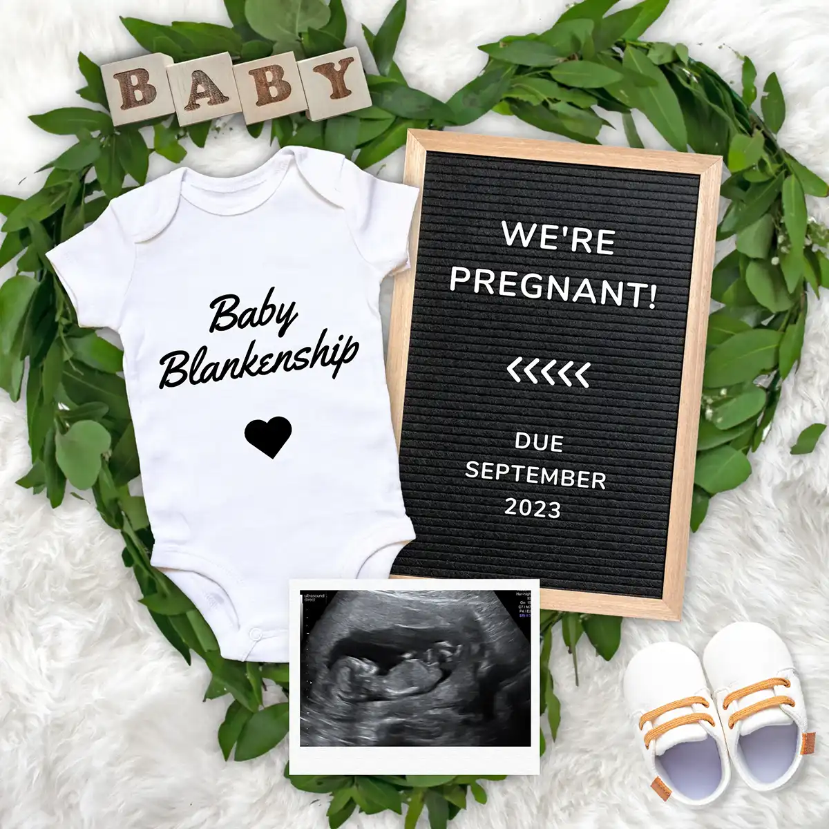 Pregnancy announcement flat lay with personalized baby onesie, We're Pregnant letterboard, ultrasound photo, and baby shoes.