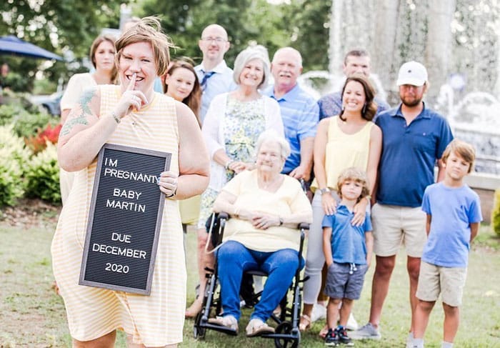 family photoshoot where a woman is about to announce her pregnancy with a letter board