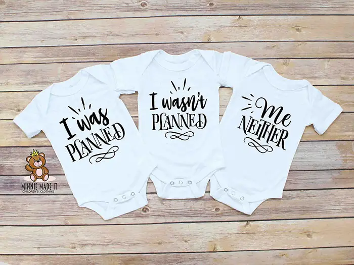 three onesie bodysuits that read "I was planned," "I wasn't planned," and "me neither"