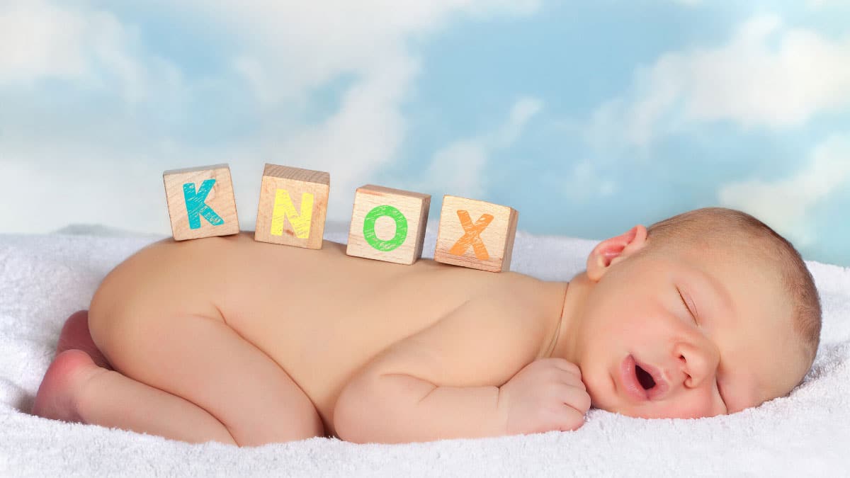 baby sleeping with letter blocks on his back spelling Knox