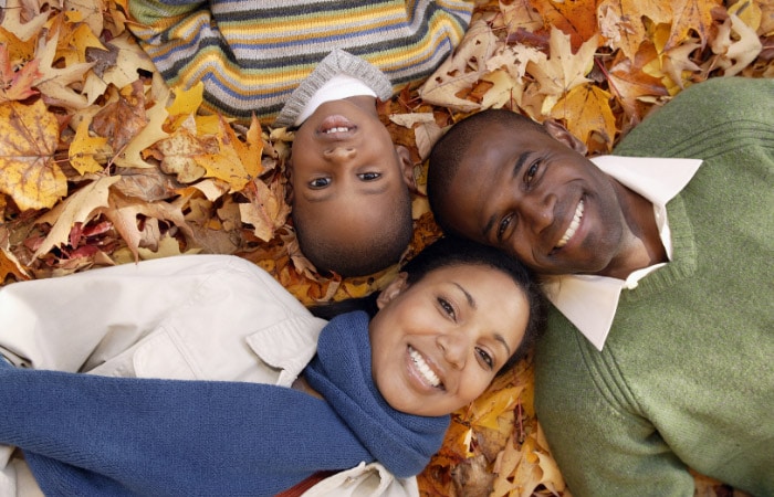 aerial view of Black family of three lying in the leaves for fall family photos