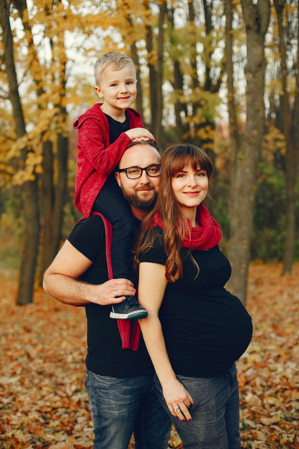 pregnant couple and son posing for family pictures in the fall