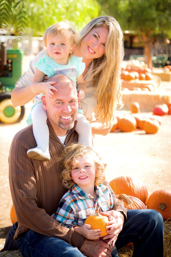 family of four posing for fall pictures in a pumpkin patch
