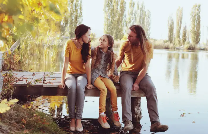 couple with child sitting on a small pier in the fall