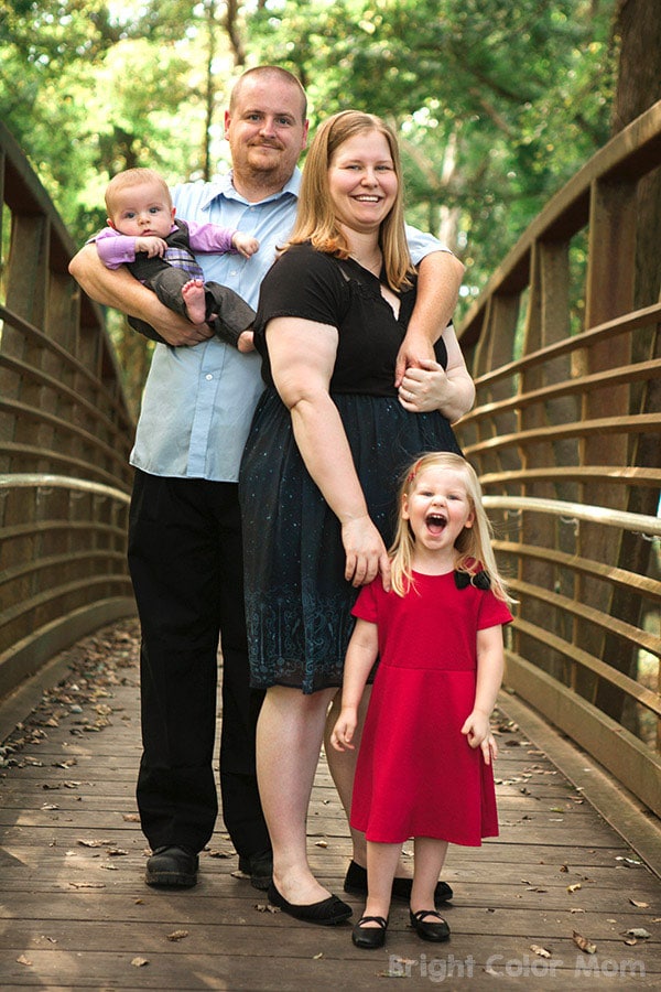 family with plus size mom, young girl and baby boy standing on a bridge in the fall