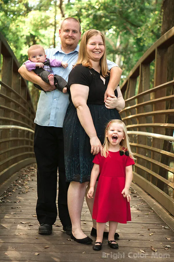 family with plus size mom, young girl and baby boy standing on a bridge in the fall