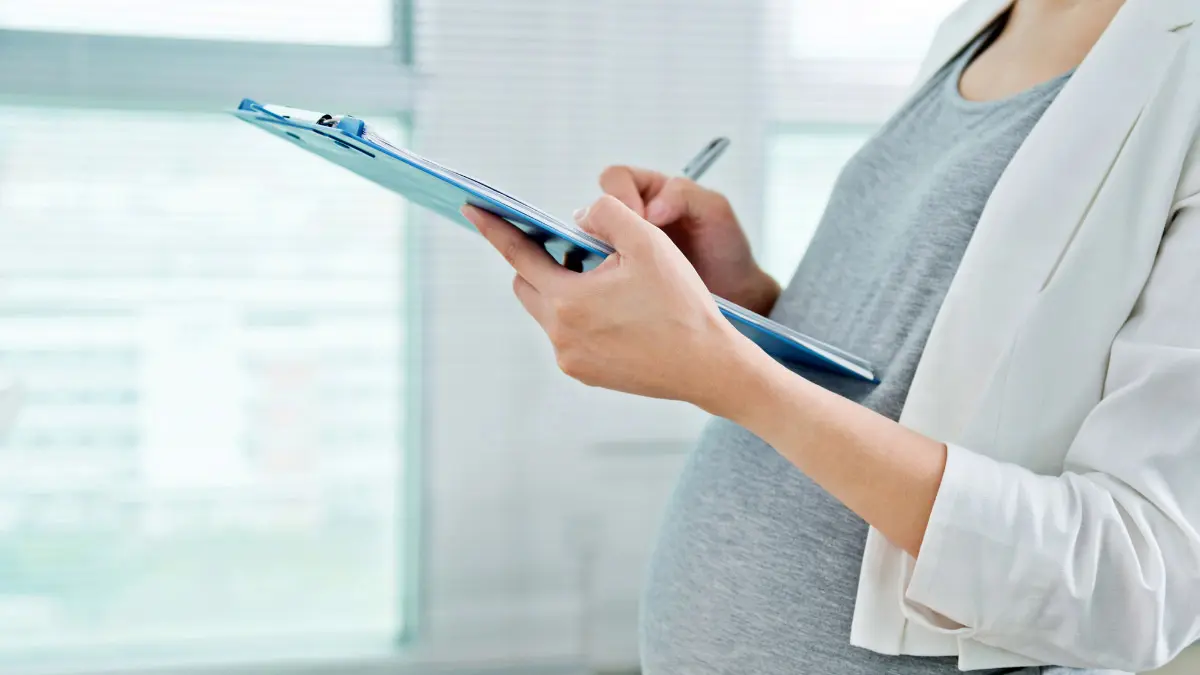 pregnant woman planning her gender reveal party with a pen and clipboard