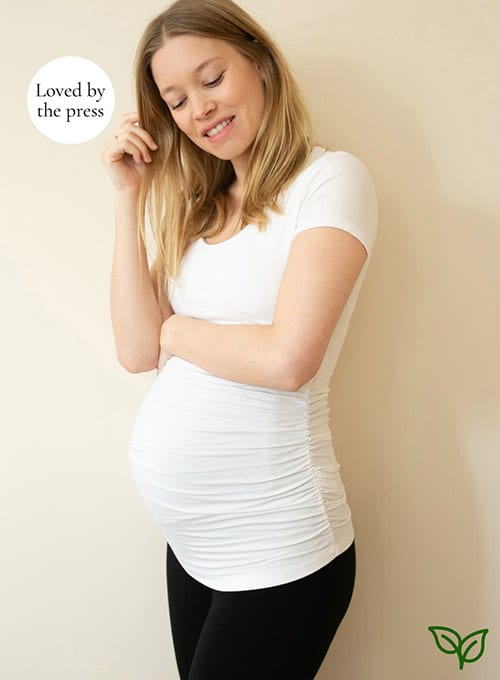 pregnant woman wearing a white cap-sleeved scoop-necked ruched maternity shirt