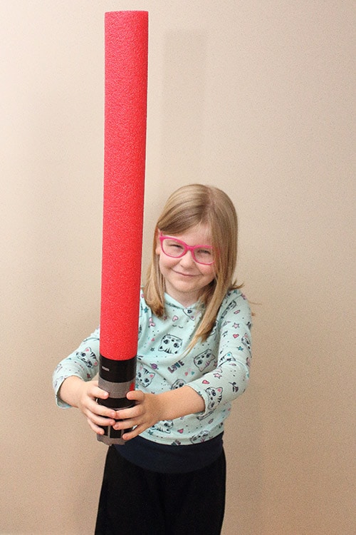 little girl holding pool noodle lightsaber like Darth Vader's