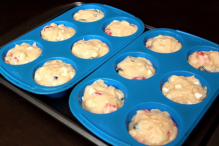 fruit-filled muffin batter spooned into a dozen muffin cups