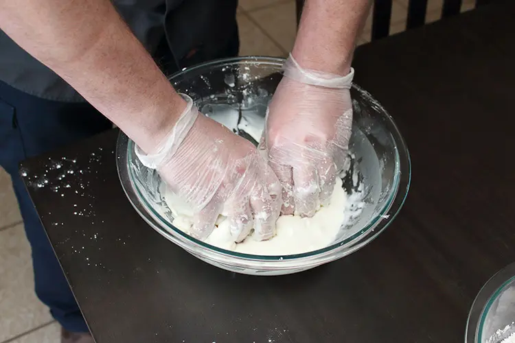 cornstarch and water being mixed together by gloved hands