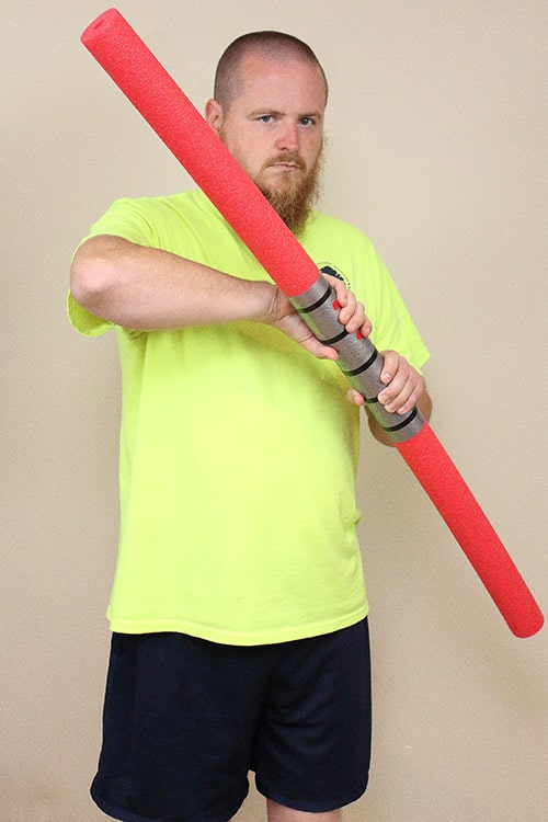 man holding double-bladed foam lightsaber made to look like Darth Maul's