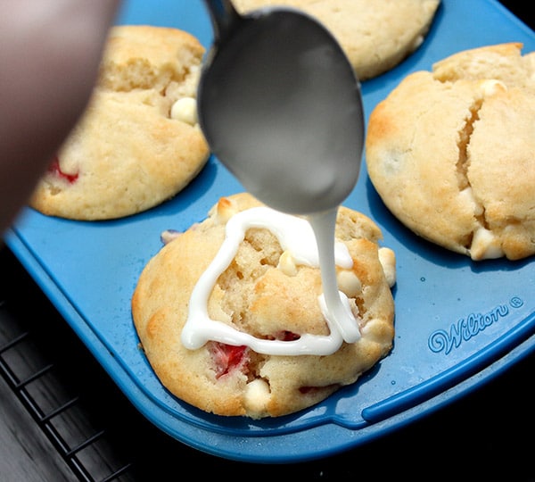 white glaze being drizzled onto red, white and blue muffins