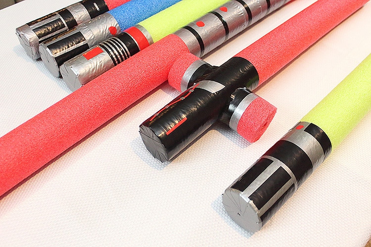 the hilts of pool noodle lightsabers made to mimic Darth Vader's, Anakin Skywalker's, Luke Skywalker's, Darth Maul's, Kylo Ren's, and Yoda's lightsabers