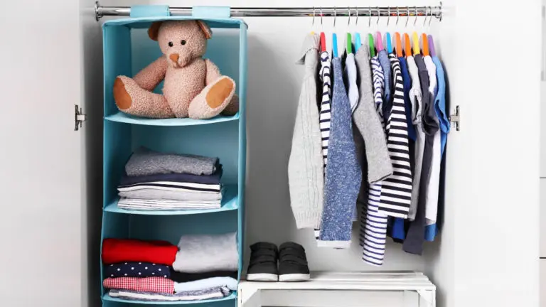 the inside of a young child's closet, featuring hanging bins with a teddy bear and shirts on hangers