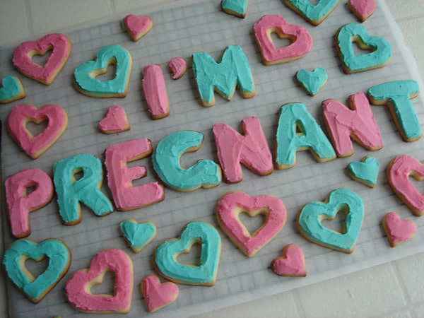 pink and blue frosted cookies that spell out "I'm pregnant" with hearts
