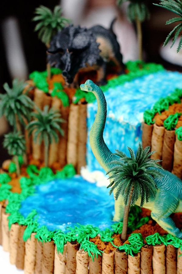 closeup of a brachiosaurus toy on a dinosaur themed birthday cake