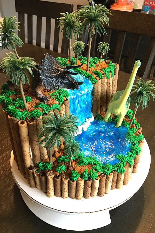 side view of a homemade dinosaur birthday cake with waterfall and trees