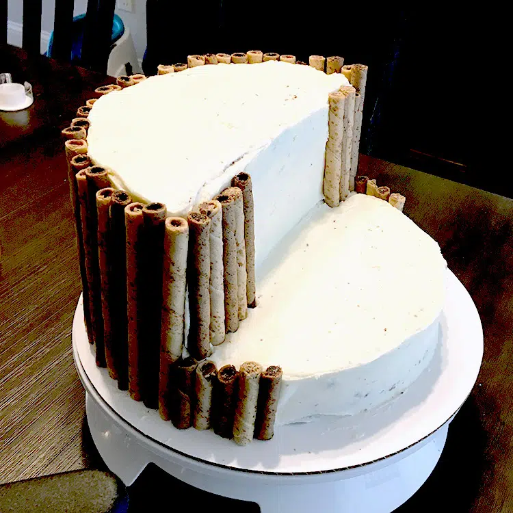 waterfall cake in progress with exposed buttercream frosting and pirouette cookies as the sides of the cliff