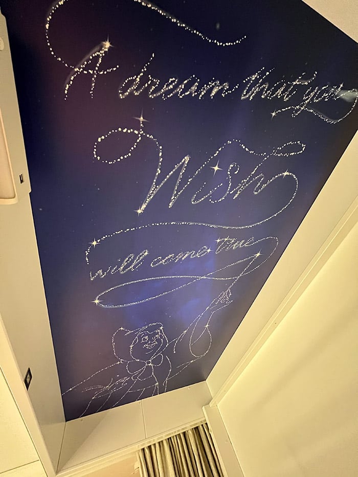 a dark blue ceiling with stars constellating into an image of the Fairy Godmother and the words "A dream that you wish will come true"