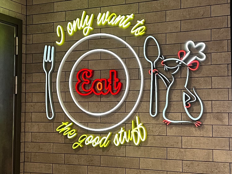 neon sign in Marceline Market on the Disney Wish featuring Remy from the movie Ratatouille and the phrase "I only want to eat the good stuff"