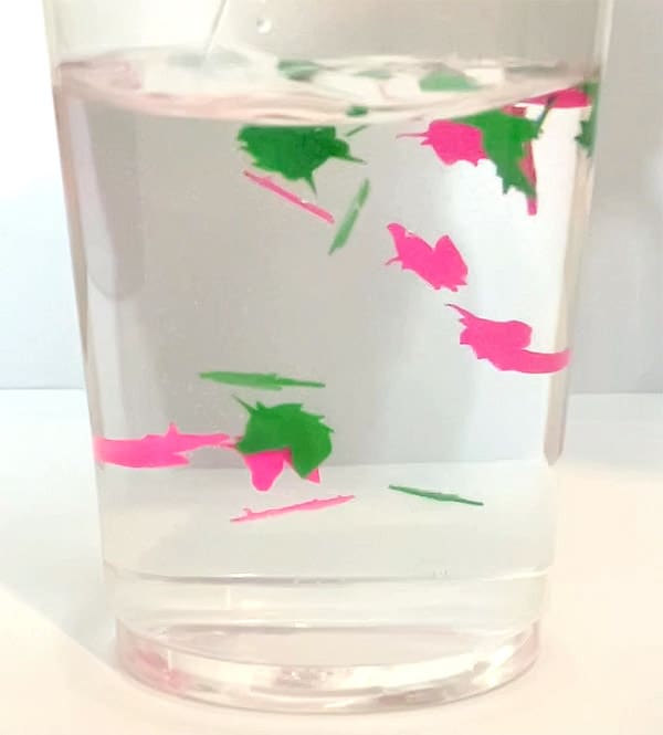 green and pink unicorn plastic material waterproof confetti floating around in cup of water