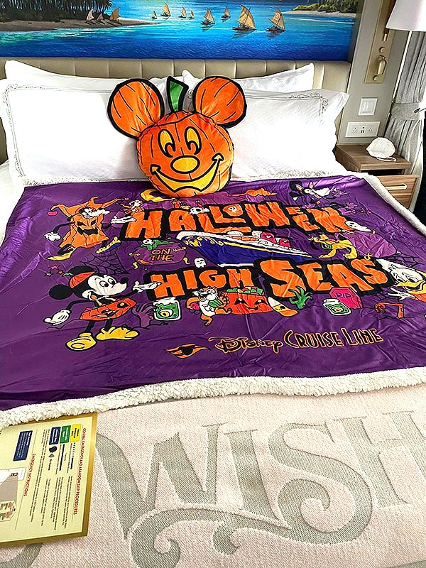 a bed on the Disney Wish with purchased Halloween stateroom decor (a blanket and pillow) on it