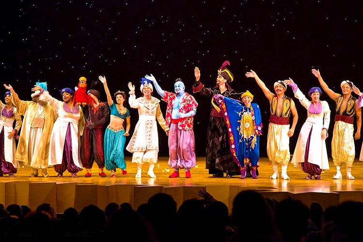 the cast of the Aladdin theatre show on stage waving