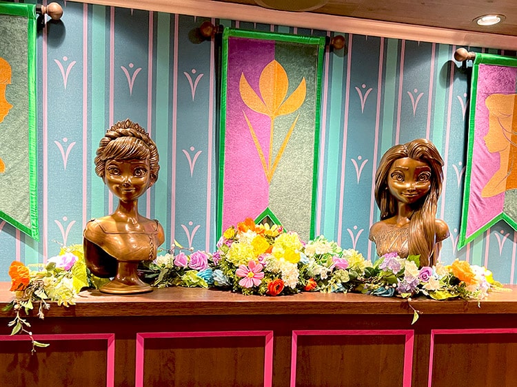 bronze busts of Anna and Elsa with a garland of summer flowers between them
