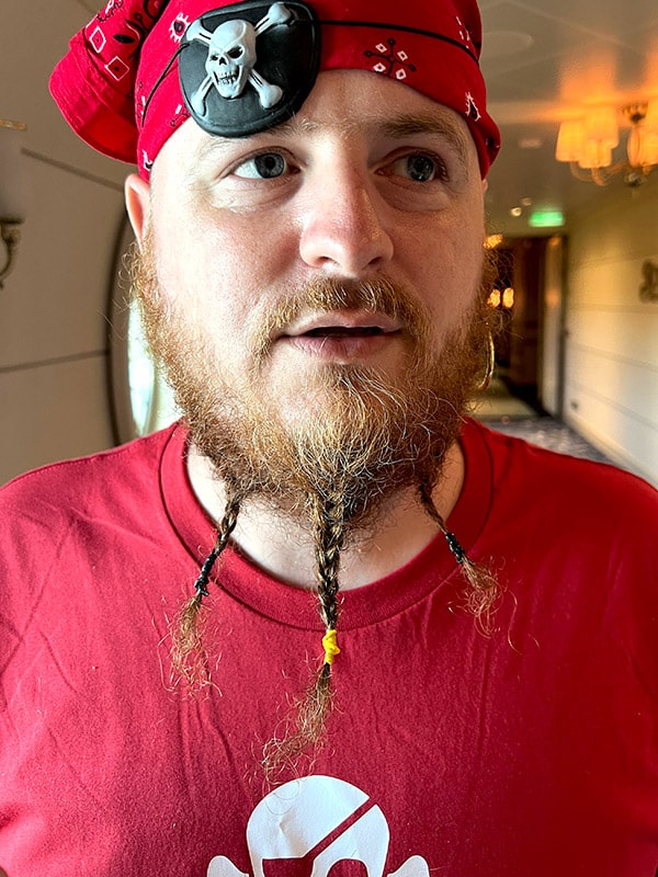 a man dressed as a pirate with a bandana and eye patch on his head with three braids in his long beard