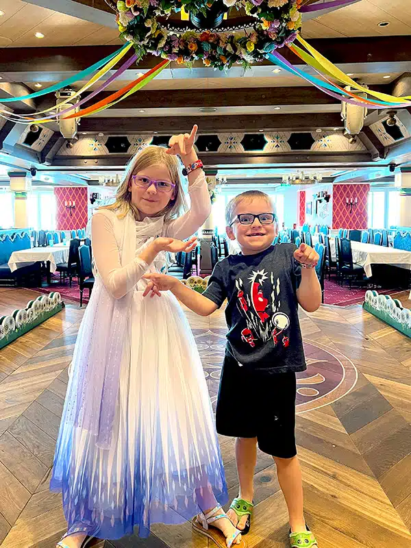 two children, one dressed as Elsa, playing on the Arendelle stage on the Disney Wish