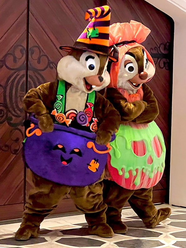 Chip and Dale dressed as a bucket of candy and a poisoned apple, respectively, aboard the Disney Wish