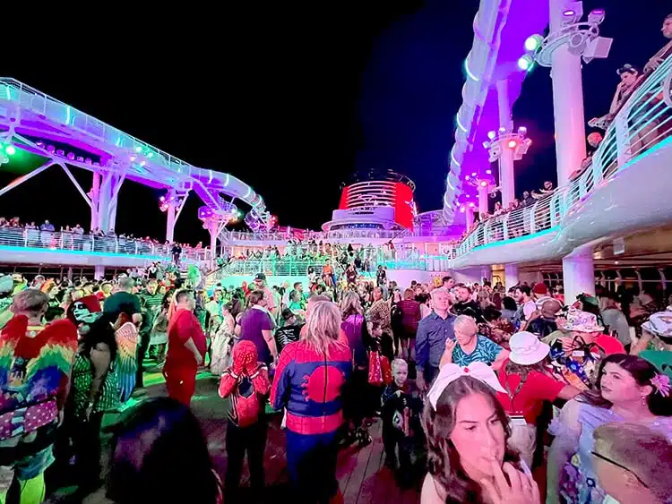 a large crowd on the pool deck of Disney Wish at night