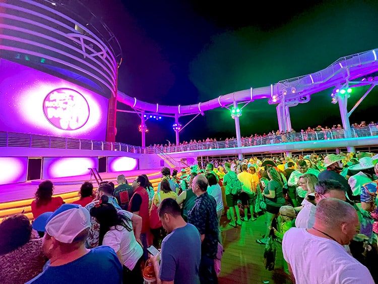 a wide shot of the crowd on the pool deck at Mickey's Mouse-querade Party on the Disney Wish