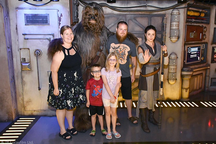 a family posing with Chewbacca and Rey from Star Wars on the Disney Wish