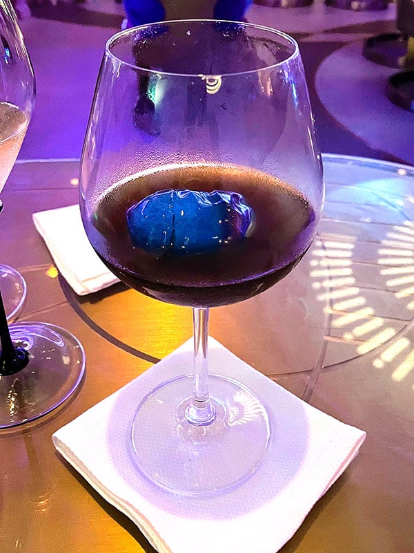 the Freetown Reserve drink from the Disney Wish, a dark smoky liquor that's been poured over a special blue ice cube