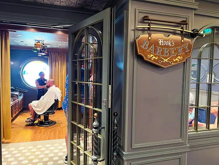 view of a man seated in a salon chair inside a shop with a sign reading "Hook's Barbery" on the outside