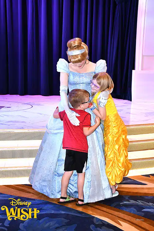 a boy and girl hugging Cinderella on the Disney Wish ship